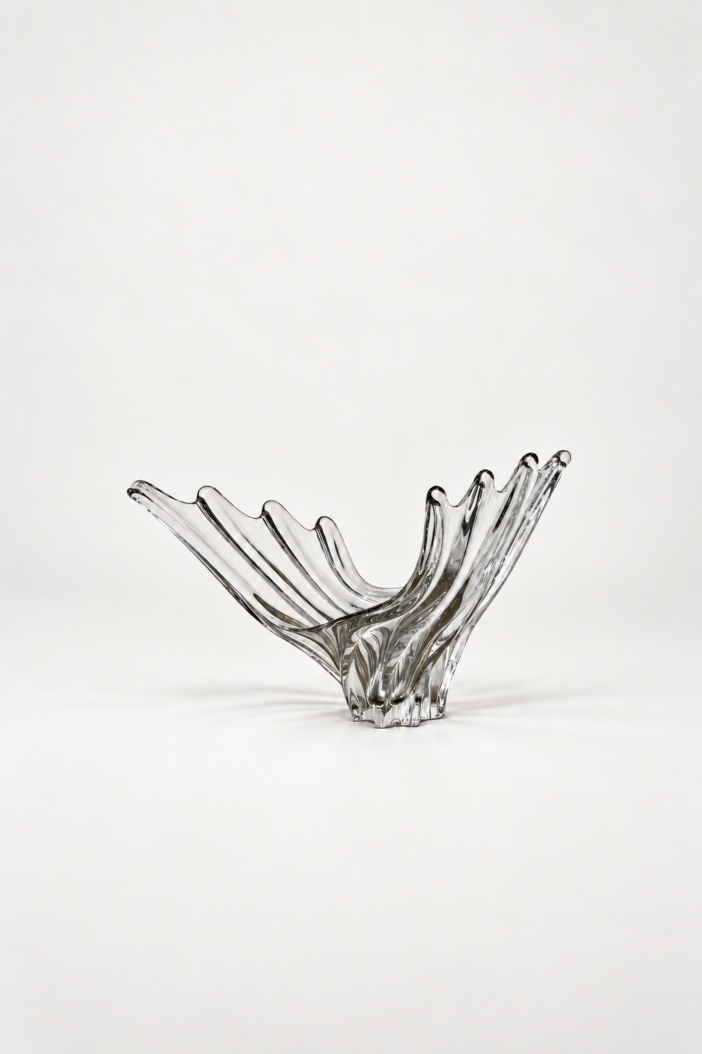 VANNES GLASS, A CLEAR FRENCH CRYSTAL WING BOWL WITH FLUTED RIDGES RISING FROM A STAR SHAPED FOOT, ON WHITE