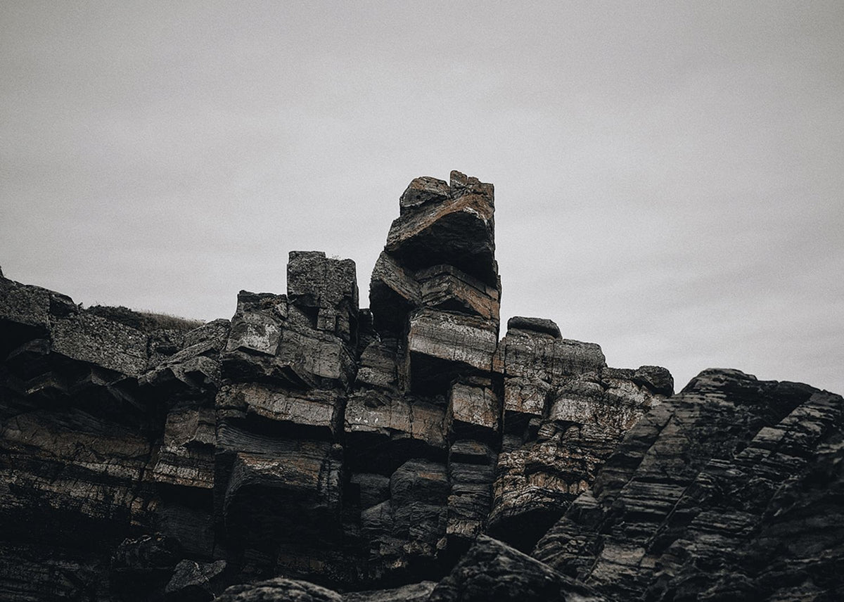 TARLAIR. LAYERED ROCK STACKS UNDER A PALE SKY, IN BLACK AND WHITE